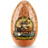 Na zdjęciu znajduje się pomarańczowe jajko z pęknięciami, na którym widnieje ilustracja triceratopsa oraz napis "DINO PUZZLE EGG TRICERATOPS".