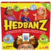 Czerwone pudełko gry karcianej z dużym napisem "HEDBANZ" na środku, poniżej którego znajduje się tekst: "The quick question game of 'What am I?'". Na pudełku widoczne są ilustracje trzech postaci z opaskami na głowach, a w dolnym rogu znajduje się ostrzeż