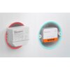 Na zdjęciu znajdują się dwa inteligentne przełączniki SONOFF Smart Switch ZBMINIL2, umieszczone w okrągłych wnękach na ścianie, z podświetleniem w kolorach czerwonym i niebieskim. Na obudowach widoczne są oznaczenia techniczne oraz logo "SONOFF".