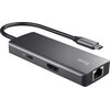 Na zdjęciu znajduje się hub USB typu C w kolorze szarym z kilkoma portami, w tym HDMI i Ethernet, oraz widocznym logo "TRUST" na obudowie. Hub jest połączony z kablem zakończonym wtykiem USB typu C.