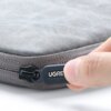 Szare etui na laptopa z widocznym zamkiem błyskawicznym, na którym znajduje się logo "UGREEN". Na zdjęciu widać dłoń trzymającą suwak zamka.