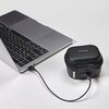 Na zdjęciu znajduje się otwarty laptop z podłączonym kablem USB, który łączy się z czarnym etui. Na etui widoczny jest napis "WIRELESS GO II" oraz logo "RODE".