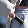 Osoba trzyma czarny statyw ULANZI RMT-01, wkładając go do kieszeni szarych spodni dresowych. Na statywie widoczne są przyciski oraz napis "Ulanzi".