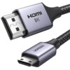 Na zdjęciu widoczny jest kabel HDMI z końcówkami HDMI i Mini HDMI, z metalowymi obudowami, na których znajdują się napisy "HDMI 8K" oraz "UGREEN". Kabel ma plecioną osłonę, co sugeruje jego wytrzymałość.