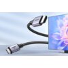 Na zdjęciu znajduje się kabel HDMI - Mini HDMI z oznaczeniem "8K" oraz logo "UGREEN" na wtyczkach, obok ekranu z wyświetlonym kolorowym kwiatem. Kabel ma plecioną osłonę i jest przedstawiony w dynamicznej pozycji.