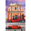 Na zdjęciu znajduje się pomarańczowy model samochodu sportowego z puzzli 3D, ustawiony na tle zabytkowego budynku z pomarańczową fasadą i białymi kolumnami. Na samochodzie widoczne są linie puzzli, a w tle niebo jest różowo-fioletowe.