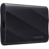 Czarny dysk zewnętrzny o teksturowanej powierzchni, z widocznym logo "SAMSUNG" oraz portem USB. Produkt ma zaokrąglone krawędzie i kompaktowy kształt.