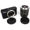 Aparat Canon EOS bez obiektywu, obok niego znajduje się obiektyw Canon 18-55mm oraz dwa czarne dekielki z oznaczeniem "C/M".