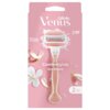 Różowe opakowanie z golarką i dwoma wkładami, ozdobione kwiatowymi motywami. Widoczny tekst: "Gillette Venus ComfortGlide Spa Breeze", "Skin Cushion", "3", "2".