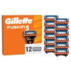 Pomarańczowe opakowanie z napisem "Gillette Fusion5" oraz grafiką przedstawiającą ostrze do golarki, obok którego znajduje się liczba "12" z ikoną ostrzy. Obok opakowania widocznych jest dwanaście wymiennych ostrzy do golarki ułożonych w trzech kolumnach.