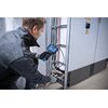 Na zdjęciu osoba używa przewodu kamery BOSCH Professional GIC 4/5 Imager 1600A02R6P do inspekcji wnętrza szafy elektrycznej z widocznymi kolorowymi przewodami. Osoba trzyma urządzenie z ekranem, na którym wyświetlany jest obraz z kamery.