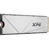 Srebrny dysk SSD z widocznym logo "XPG" na powierzchni, z elementami elektronicznymi i złotymi złączami na jednym końcu. Dysk ma geometryczne wzory na obudowie.