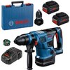 Na zdjęciu znajduje się niebieska młotowiertarka z logo "BOSCH Professional GBH 18V-34 CF", dwa akumulatory ProCORE 18V, ładowarka, dodatkowy uchwyt wiertarski oraz niebieska walizka z napisem "BOSCH".