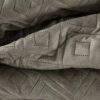 Ciemnobeżowa narzuta z widocznym geometrycznym wzorem w formie rombów, wykonana z miękkiego materiału. Wzór składa się z małych, regularnych kropek tworzących kontury rombów.
