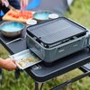 Na zdjęciu znajduje się grill turystyczny z napisem "CAMPINGAZ Camp Bistro Grill" ustawiony na stole, obok którego leży tacka z resztkami sosu. W tle widoczne są miski i deska do krojenia z pokrojonymi warzywami.