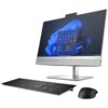 Na zdjęciu znajduje się komputer stacjonarny typu all-in-one z ekranem wyświetlającym interfejs systemu Windows 11, klawiatura oraz myszka. Na obudowie monitora widoczne jest logo "Bang & Olufsen".