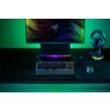 Na zdjęciu znajduje się biurko z klawiaturą RAZER Huntsman V3 Pro TKL, myszką na podkładce, stojakiem z zestawem słuchawkowym oraz monitorem z kolorowym wzorem i logo Razer. Wszystkie urządzenia są podświetlone w różnych kolorach, tworząc efektowne oświet
