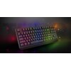 Czarna klawiatura mechaniczna z podświetleniem RGB, na której widoczne są klawisze z oznaczeniami liter i funkcji, takimi jak "Esc", "Shift" i "Enter". W tle rozmyte kolorowe światła oraz duży napis "THOR".