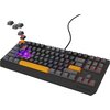 Klawiatura mechaniczna z ciemnoszarymi klawiszami i podświetleniem RGB, z kilkoma klawiszami w kolorze pomarańczowym. Na zdjęciu widoczne są również zdjęte klawisze, ukazujące czerwone przełączniki, oraz logo "GENESIS" na obudowie.