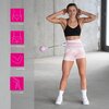 Na zdjęciu widoczny jest różowy hula hop z przymocowanym ciężarkiem oraz czarny pas wyszczuplający na osobie w sportowym stroju. Po lewej stronie znajdują się ikony z napisami: "SMUKŁA TALIA", "JĘDRNE POŚLADKI", "MOCNE RAMIONA", "ZGRABNE UDA".