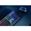 Na zdjęciu widoczna jest czarna klawiatura z podświetleniem RGB oraz myszka na ciemnym tle. Klawiatura ma niskoprofilowe klawisze i widoczny jest pasek regulacji głośności.