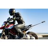 Na zdjęciu widoczny jest motocyklista w czarnym kombinezonie i kasku, jadący na czerwono-czarnym motocyklu. Motocykl ma zamontowany uchwyt na kamerę, a w tle widać niebo i rozmyty krajobraz.