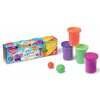 Na zdjęciu znajduje się opakowanie z napisem "Maped Creativ" oraz "Pot Dough", obok którego widoczne są cztery pojemniki z kolorową masą plastyczną w kolorach pomarańczowym, fioletowym, zielonym i różowym. Na opakowaniu znajduje się również ilustracja fio