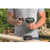 Mężczyzna w szarej koszulce trzyma wiertarko-wkrętarkę BOSCH AdvancedImpact 18V-80, a na drewnianej desce leży bateria z widocznym logo BOSCH i napisem "18V 2.5Ah". W tle znajduje się rozmyte otoczenie z zielenią i metalowym ogrodzeniem.
