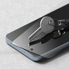 Na zdjęciu widoczny jest smartfon z nałożonym szkłem hartowanym, na którym leży metalowy klucz. Na kluczu znajduje się napis: "PRIMA FABBRICA CISA".