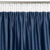 Granatowa zasłona z białą taśmą marszczącą u góry, zawieszona na metalowym karniszu. Materiał zasłony ma delikatną fakturę i jest równomiernie pofałdowany.