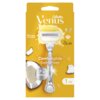 Opakowanie golarki Gillette Venus Comfortglide Coconut Scent z widocznym ostrzem otoczonym żółtym żelem, obok kawałki kokosa i krople płynu. Na opakowaniu znajdują się napisy: "Skin Cushion", "5", "Plus Olay", "Comfortglide Coconut Scent", "Platinum", "Ve
