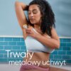 Osoba w jasnym stroju używa golarki na skórze pod pachą, na tle niebieskich płytek. Na zdjęciu widoczny jest tekst: "Trwały metalowy uchwyt".