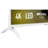 Na zdjęciu widoczny jest fragment telewizora z białą ramką i podstawą, na ekranie którego znajduje się tekst: "4K | LED | Dolby AUDIO". Tło ekranu jest w odcieniach zieleni i żółci.