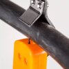 Na zdjęciu widoczny jest fragment narzędzia do ściągania izolacji, które obejmuje czarny przewód. Narzędzie ma pomarańczowy element z dwoma okrągłymi otworami.