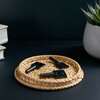 Na zdjęciu widoczne są trzy czarne klucze z napisem "Netatmo" leżące na okrągłej, plecionej podstawce. W tle znajdują się stos książek oraz roślina w białej doniczce.