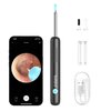 Na zdjęciu znajduje się czarny otoskop z kamerą, obok którego widoczny jest smartfon z aplikacją pokazującą obraz wnętrza ucha. W zestawie znajdują się również wymienne końcówki, przezroczysty pojemnik oraz kabel USB; na otoskopie widnieje logo "bebird".