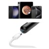 Na zdjęciu znajduje się czarny otoskop z kamerą oraz kabel USB. W tle widoczne są trzy urządzenia mobilne, z których jedno pokazuje obraz wnętrza ucha.