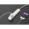Na zdjęciu znajduje się biały przedłużacz z kilkoma gniazdami, do którego podłączona jest ładowarka z kablem USB-C - Lightning, łącząca się z telefonem o wyświetlaczu z gradientem fioletowo-niebieskim. Kabel jest opisany jako "Kabel USB-C - Lightning MONT