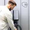 Na zdjęciu widoczna jest ładowarka do samochodu elektrycznego z logo "GC" na obudowie, zamontowana na ścianie, z przewodem zwiniętym na uchwycie. Obok ładowarki znajduje się napis "Made in Poland".