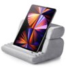 Szara, miękka podstawka do tabletu z trzema poziomymi rowkami, na której umieszczony jest tablet z kolorowym, abstrakcyjnym wzorem na ekranie. Podstawka ma kształt przypominający złożoną poduszkę.