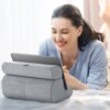 Na zdjęciu widoczna jest szara podstawka do tabletu, na której umieszczony jest tablet. W tle znajduje się osoba w jasnej bluzce, uśmiechająca się.