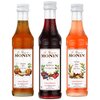 Na zdjęciu znajdują się trzy butelki syropów marki MONIN o pojemności 50 ml każda, z etykietami opisującymi smaki: Pumpkin Spice, Spiced Red Berries i Winter Spice. Na etykietach widnieje napis "Le Sirop de MONIN", a także ilustracje składników związanych z każdym smakiem.