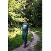 Mężczyzna w zielonej koszulce roboczej NEO TOOLS Outdoor 81-644-S spaceruje po ścieżce w lesie, otoczony bujną zielenią drzew i krzewów. Koszulka ma nadruk przedstawiający białe drzewa na tle ciemniejszego odcienia zieleni.