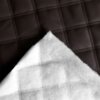 Brązowa tapicerka drzwiowa z widocznym wzorem w kratę, wykonana z materiału o fakturze skóry, z białą, miękką podszewką widoczną w rogu.