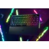 Na zdjęciu znajduje się klawiatura mechaniczna z podświetleniem RGB, z widocznym logo producenta na podpórce na nadgarstki. Klawisze są podświetlone w różnych kolorach, a w tle widać rozmyte, kolorowe światła.