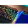 Na zdjęciu widoczna jest klawiatura z podświetleniem RGB, z klawiszami oznaczonymi literami i cyframi oraz przyciskiem "enter". Obok klawiatury znajduje się podkładka z niebieskim podświetleniem.