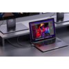 Na zdjęciu widać laptop podłączony do monitora za pomocą czarno-srebrnego kabla USB-C - DisplayPort. Na ekranie laptopa wyświetlony jest kolorowy obraz postaci w czerwonej kurtce i żółtym kapeluszu, a kabel jest widoczny na biurku.