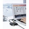 Na zdjęciu widać laptopa z otwartym systemem operacyjnym, na którym wyświetlane są foldery i pliki z chińskimi znakami, a obok znajduje się hub USB z podłączonymi urządzeniami. Na biurku stoi filiżanka z napojem, a w tle widoczny jest rozmyty krajobraz z 