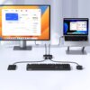 Na zdjęciu znajduje się biurko z monitorem i laptopem, które są połączone z przełącznikiem UGREEN CM757. Na biurku widoczne są także klawiatura i mysz, a na ekranie monitora wyświetlane są wykresy i dane finansowe.