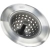 Stalowe sitko do odpływu z otworami i uchwytem pośrodku, z widocznym logo "OXO" na krawędzi. Produkt ma gładkie, metaliczne wykończenie.